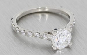 A Classic Round Brilliant Diamond Ring Accentuated With Elegant Diamond Shoulders.