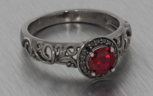 Black rhodium plated ring set with black diamonds and a round red ruby
