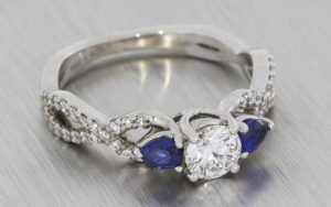 Crossover style palladium engagement ring set with diamonds and sapphires