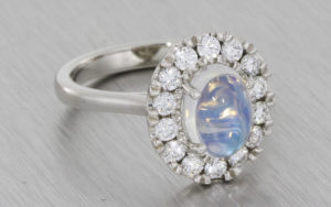 Platinum halo ring set with a moonstone and round brilliant diamonds