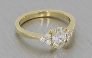 Yellow gold engagement ring featuring an oval centre diamond accented with small round diamonds