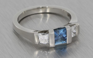 Modern engagement ring featuring square cut sapphire and diamonds